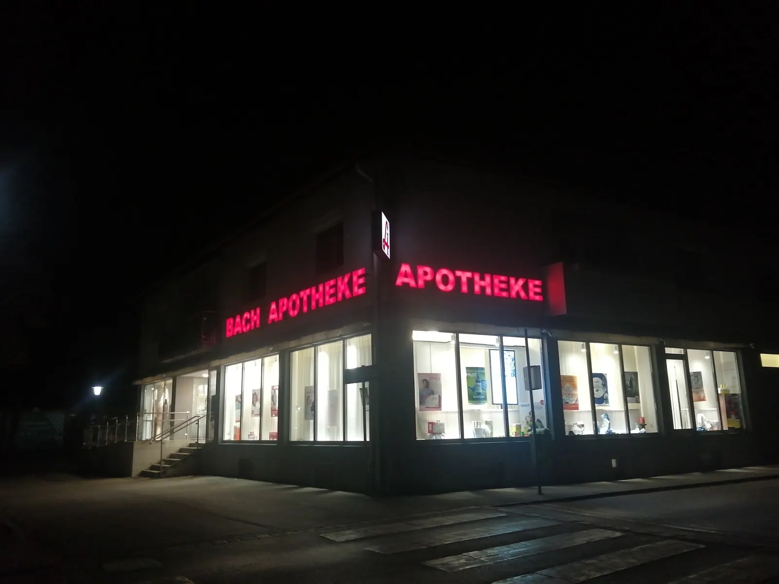 Die Bach-Apotheke in Oberwart bei Nacht mit roter Leuchtschrift und beleuchteten Schaufenstern